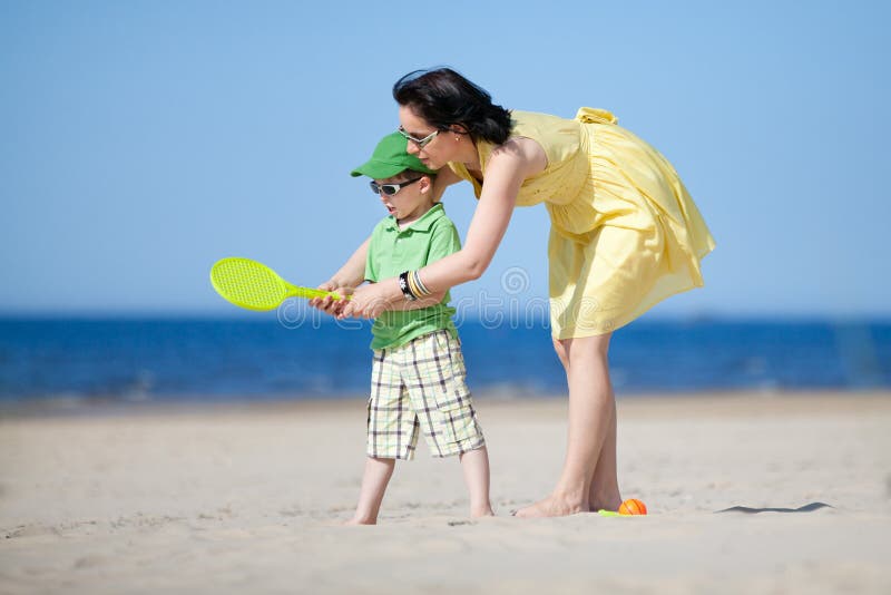 Young mother teaching her son to play tennis