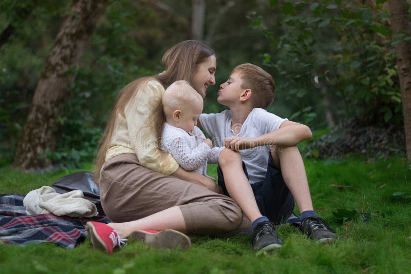 Young mother with two children resting on nature. Mother love and care. Happy family stock image Young mother with two children resting on nature. Mother love and care. Happy family stock image
