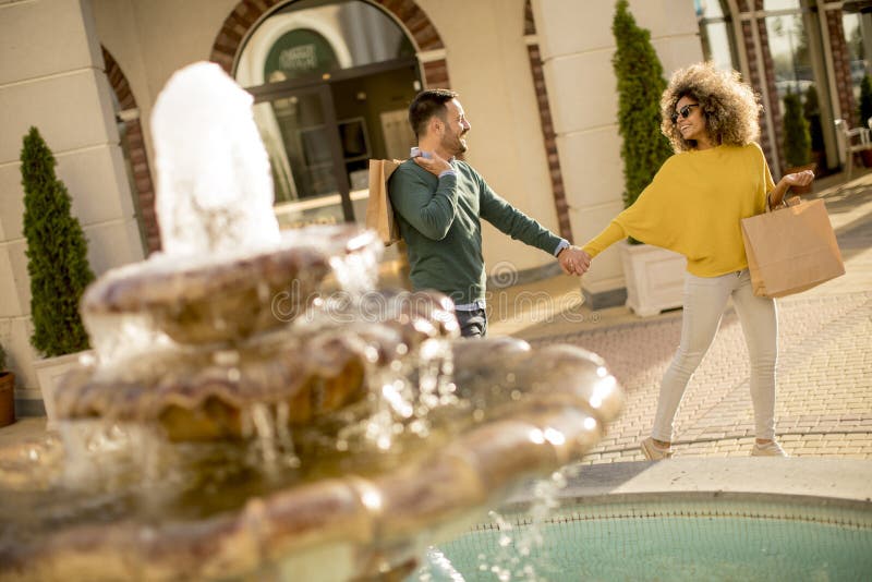 Young multiethnic couple walking by the fountain royalty free stock photography