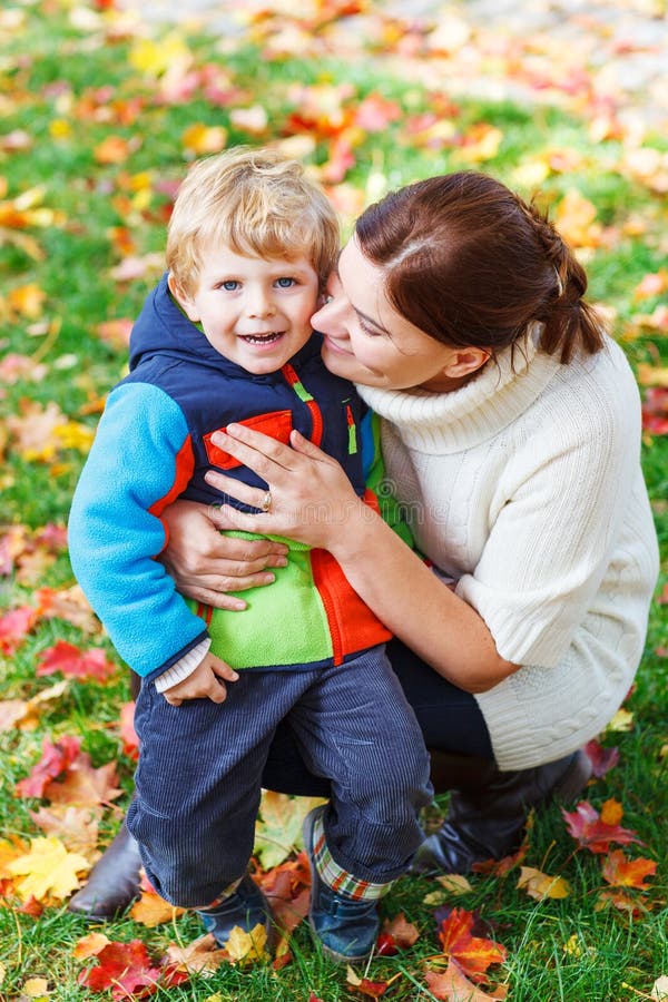 Young mum and her little kid son hugging together in autumn park