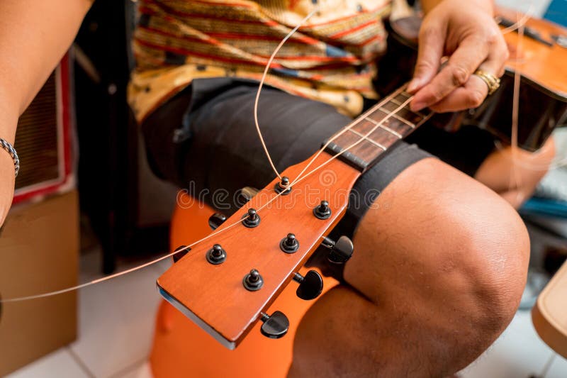 Young musician changing strings on a classical guitar in a guitar shop