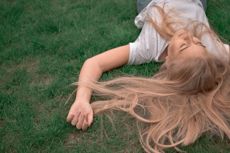 Young natural blonde woman with eyes closed lying in the green grass royalty free stock photography Young natural blonde woman with eyes closed lying in the green grass royalty free stock photography