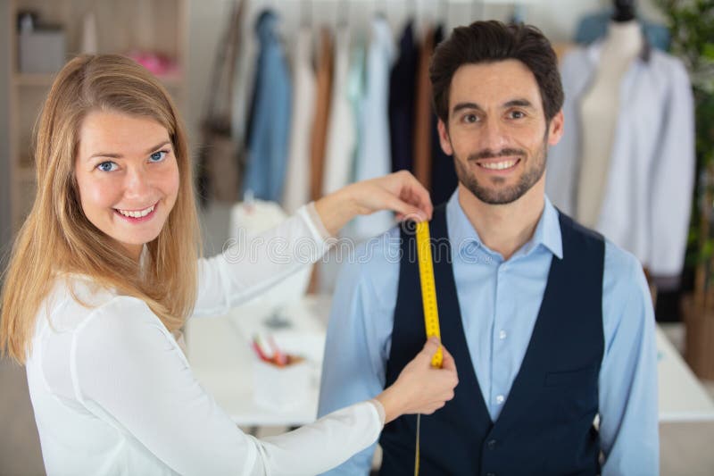 Young needlewoman taking measures male client stock images