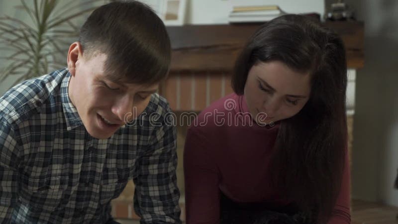 Young nice Caucasian couple looking at each other and filling out papers. Camera moving down to documents. Man and woman stock footage