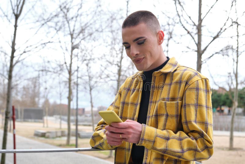 Young non binary person checking his smartphone and smiling stock photo
