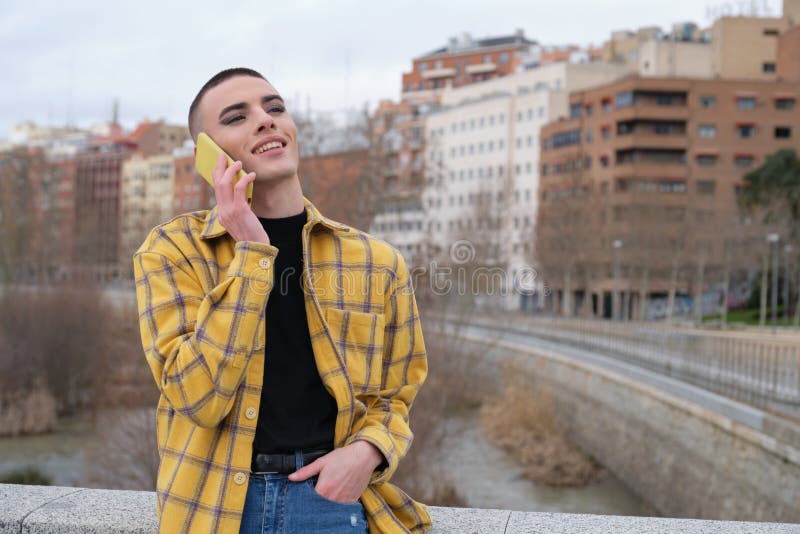 Young non binary person speaking on a smartphone laughing royalty free stock photography