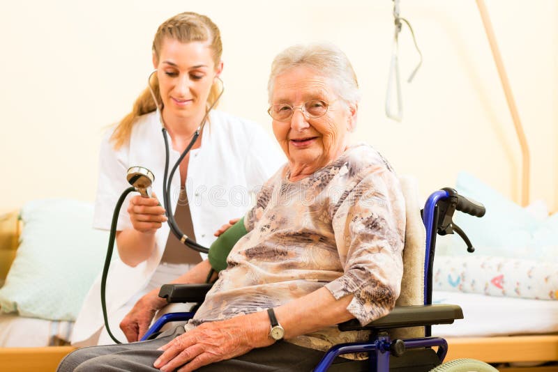 Young nurse and female senior in nursing home, the blood pressure is going to be measured