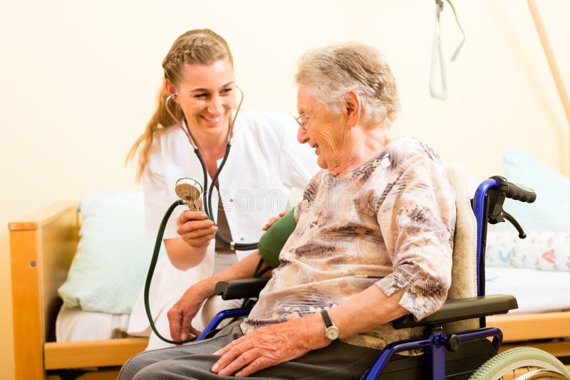 Young nurse and female senior in nursing home, the blood pressure is going to be measured