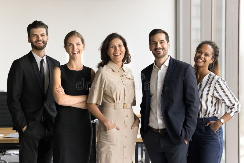 Young office employees led by mature boss posing at workplace stock images