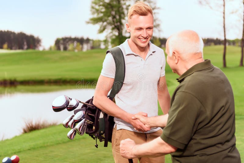 Young and old golf players shaking hands