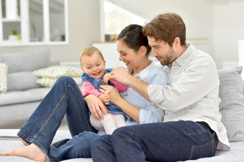 Young Parents Playing with Baby Girl on Sofa Stock Image - Image of ...