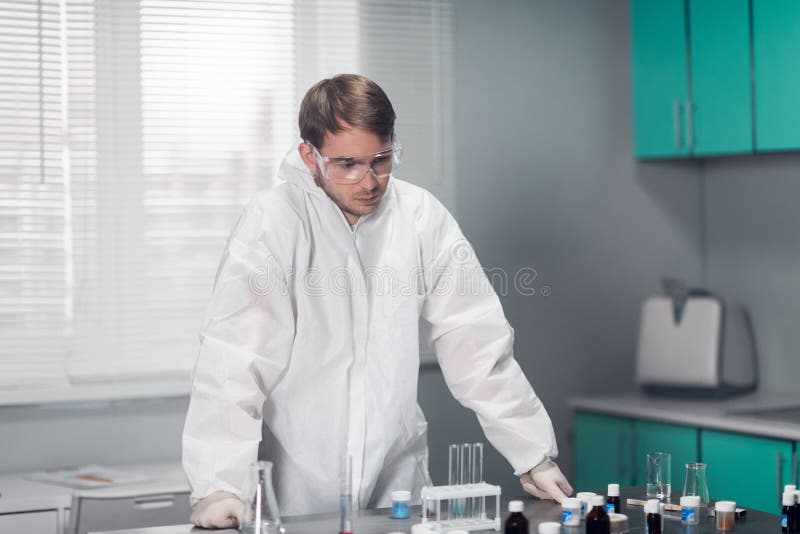 Young pensive chemist leaning on the table in a bright lab royalty free stock image