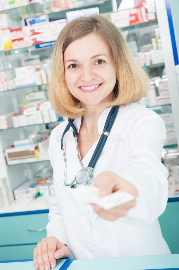 Young pharmacist with phonendoscope in drugstore giving back a prescription and change. Young pharmacist with phonendoscope in drugstore giving back a prescription and change.