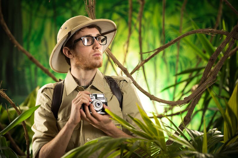 Young explorer in the jungle taking pictures with vintage camera stock imag...