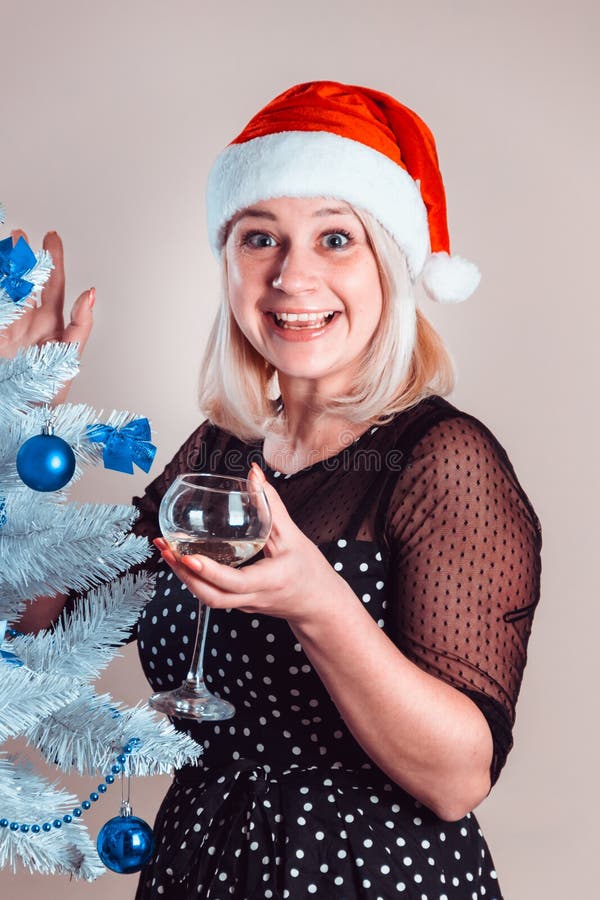 Young pleasant happy woman with glass of champagne in hand smiles. Young pleasant happy woman with glass of champagne in hand stands near white artificial stock photos Young pleasant happy woman with glass of champagne in hand smiles. Young pleasant happy woman with glass of champagne in hand stands near white artificial stock photos