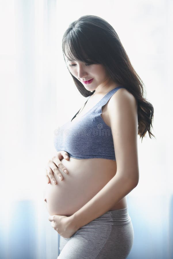Young Pregnant Asian Woman Holds Her Hands on Her Swollen Belly, Love Concept. stock photography Young Pregnant Asian Woman Holds Her Hands on Her Swollen Belly, Love Concept. stock photography