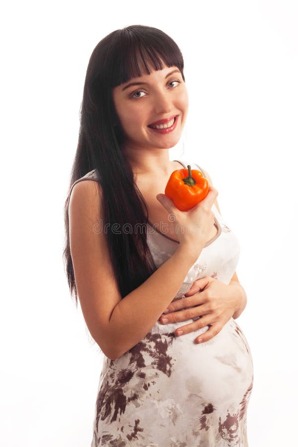 Young pregnant girl is eating pepper.