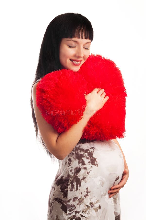 Young pregnant girl hugging a soft big heart