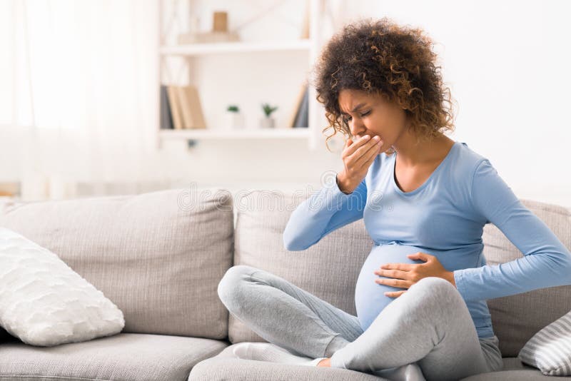 Young pregnant lady suffering with nausea, sitting on sofa royalty free stock image Young pregnant lady suffering with nausea, sitting on sofa royalty free stock image