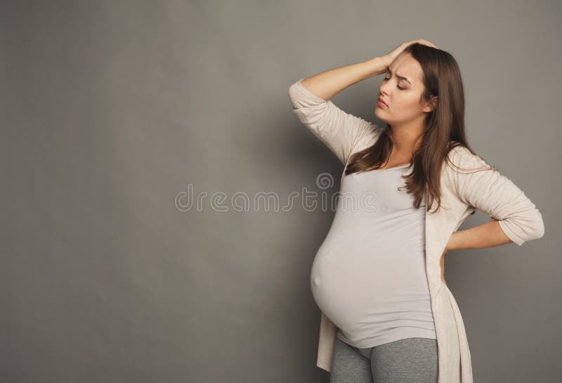 Young pregnant woman with headache at studio