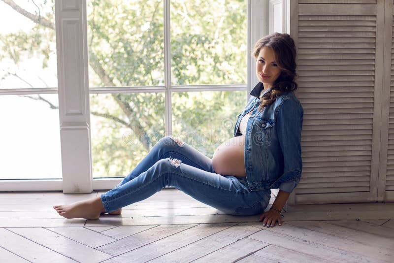 Young pregnant woman in jeans clothes in Studio