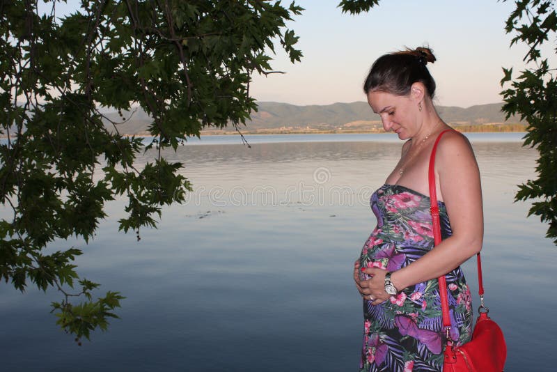 Young and pregnant woman relaxing next to the lake stock photography Young and pregnant woman relaxing next to the lake stock photography