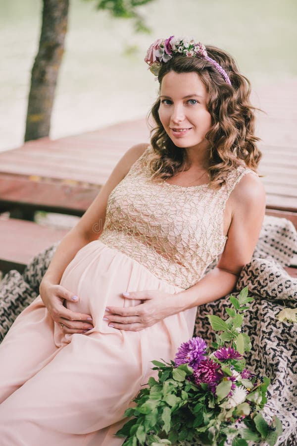 Young pregnant woman sitting near lake