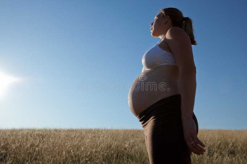 Young Pregnant Woman Standing in an Open Field