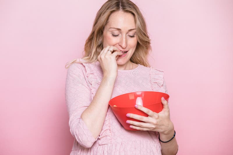 Pregnant woman eating from bowl studio shot on pink background