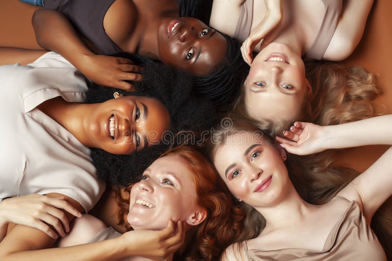 Young pretty african and caucasian women posing cheerful together on brown background, lifestyle diverse nationality