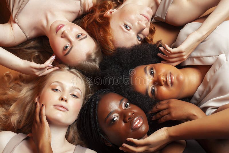 Young pretty african and caucasian women posing cheerful together on brown background, lifestyle diverse nationality