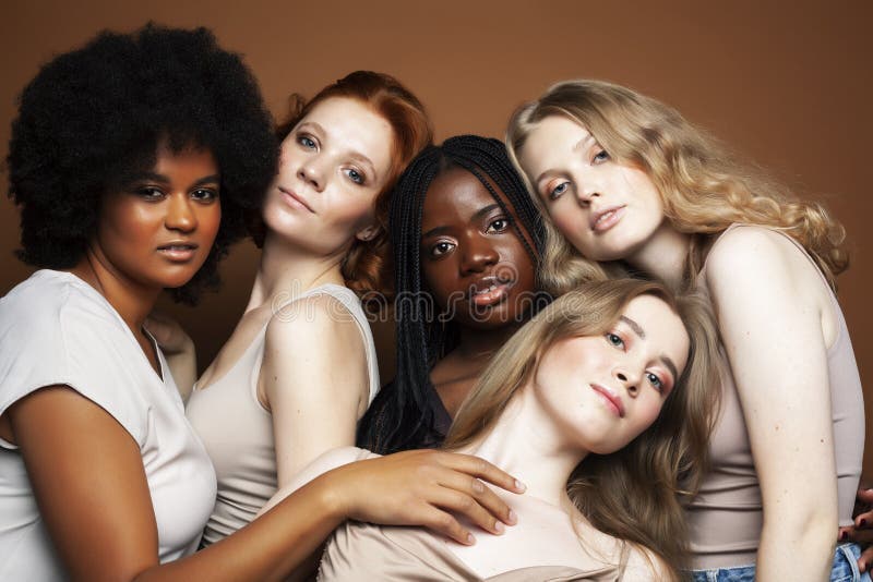 Young pretty african and caucasian women posing cheerful together on brown background, lifestyle diverse nationality