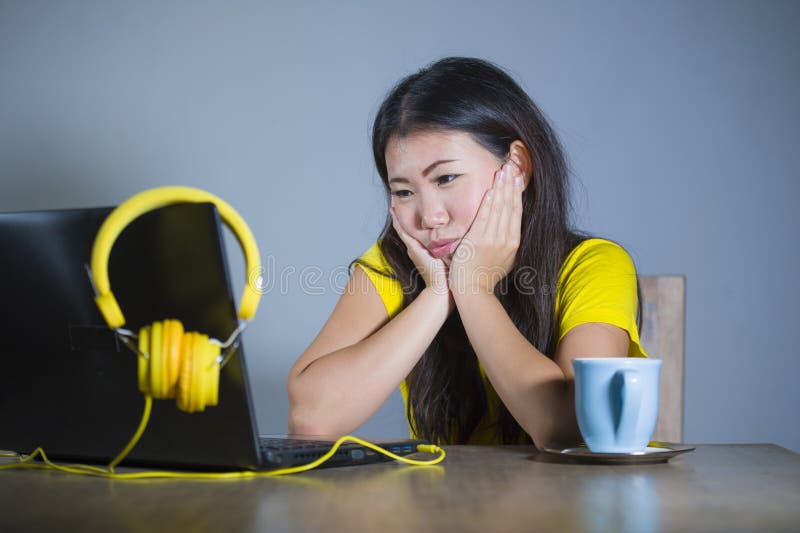 Young pretty and bored Asian Korean student girl working with laptop computer looking unhappy and sleepy holding face with hands royalty free stock photos Young pretty and bored Asian Korean student girl working with laptop computer looking unhappy and sleepy holding face with hands royalty free stock photos