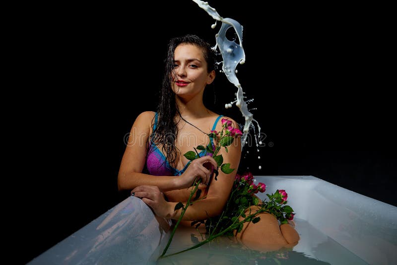 Young pretty brunette woman in bath with water and splashes and drops in a dark room stock images Young pretty brunette woman in bath with water and splashes and drops in a dark room stock images
