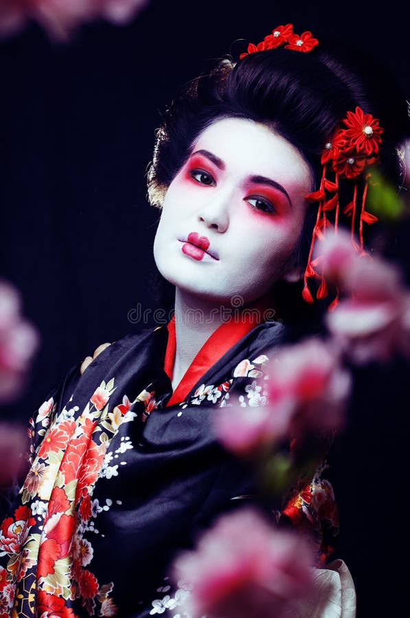 young pretty geisha in kimono with sakura and decoration on blac