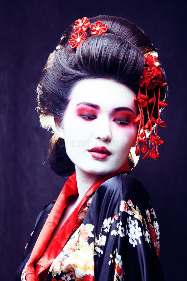 young pretty geisha in kimono with sakura and decoration on blac