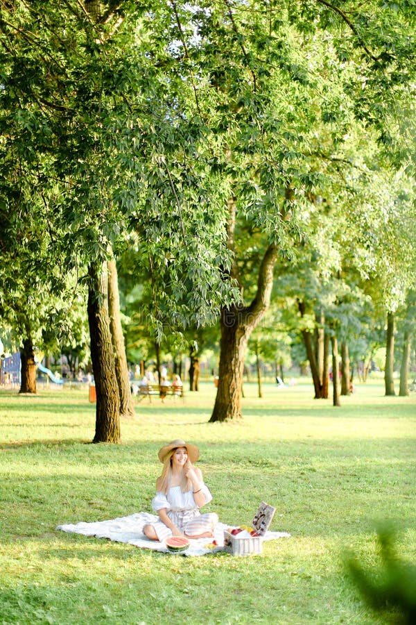 Young Pretty Girl in Hat Sitting in Garden on Plaid Near Fruits, Trees ...