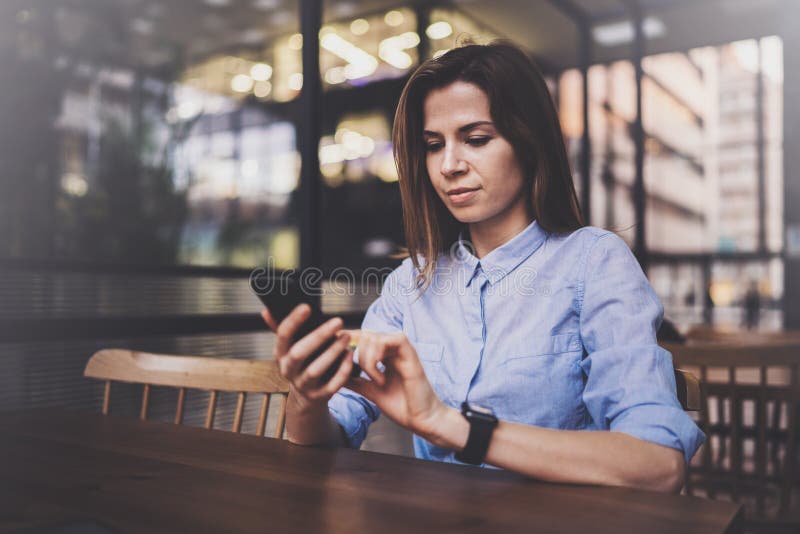Young pretty girl working on laptop and using mobile smartphone at her workplace at modern office center.Horizontal royalty free stock photo Young pretty girl working on laptop and using mobile smartphone at her workplace at modern office center.Horizontal royalty free stock photo