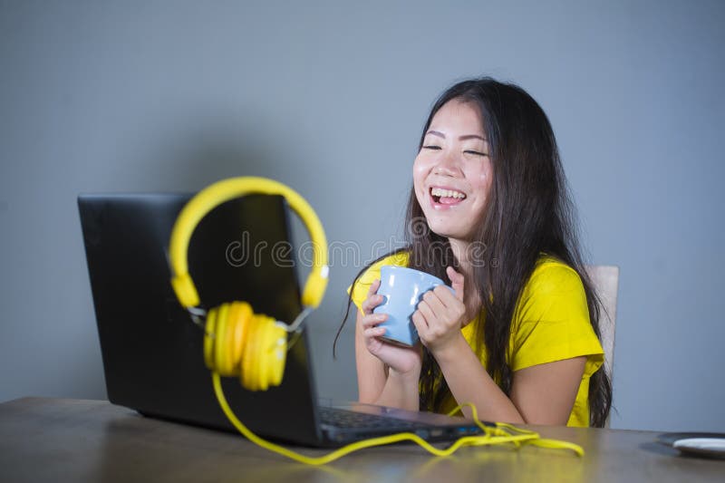Young pretty and happy Asian Korean woman at desk enjoying internet on laptop computer laughing cheerful having fun drinking tea c royalty free stock photography Young pretty and happy Asian Korean woman at desk enjoying internet on laptop computer laughing cheerful having fun drinking tea c royalty free stock photography