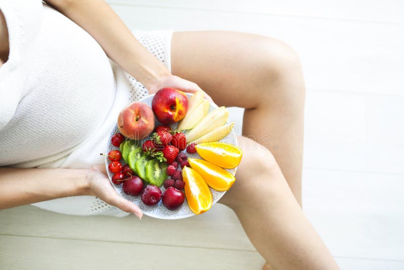 Young pretty pregnant woman with fruit plate royalty free stock photography Young pretty pregnant woman with fruit plate royalty free stock photography
