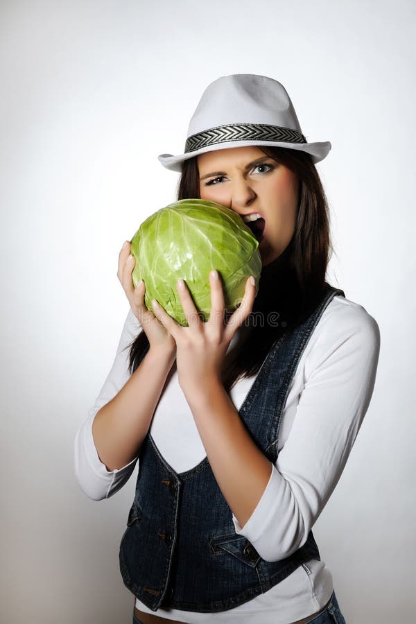 Young pretty woman eating green cabbage