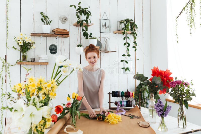 Young pretty woman looking camera while collecting bouquet in workshop