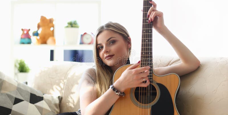 Young pretty woman playing on guitar, talented artist spend free time learning new song on musical instrument royalty free stock photo