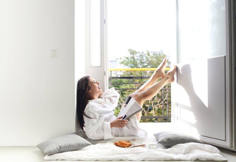 Young pretty woman reading magazine by the balcony