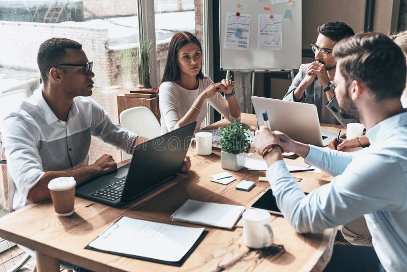 Young professional team. Top view of young modern people in smart casual wear discussing business while working in the creative o. Ffice stock images