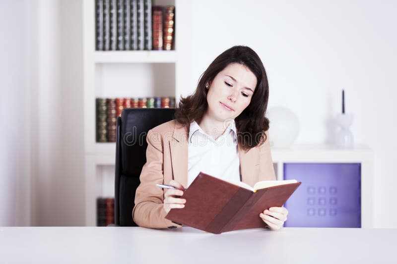 Capturing the essence of a young professional in a dynamic office setting, this image showcases a woman seamlessly managing tasks at her desk. Engaged with her computer, phone, and agenda, she embodies efficiency and ambition. Reading efficiency stock images, royalty-free photos and pictures