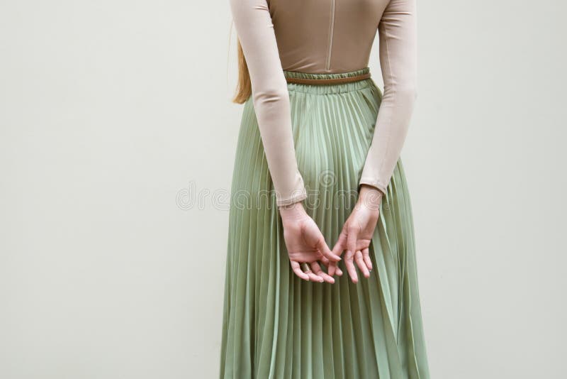 Young red hair girl in hat, dressed in beige blouse and turqoise pleats skirt, on light street backgraund.