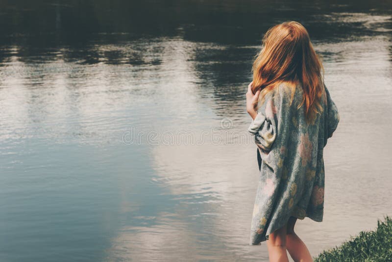 Young red hair woman walking at river alone