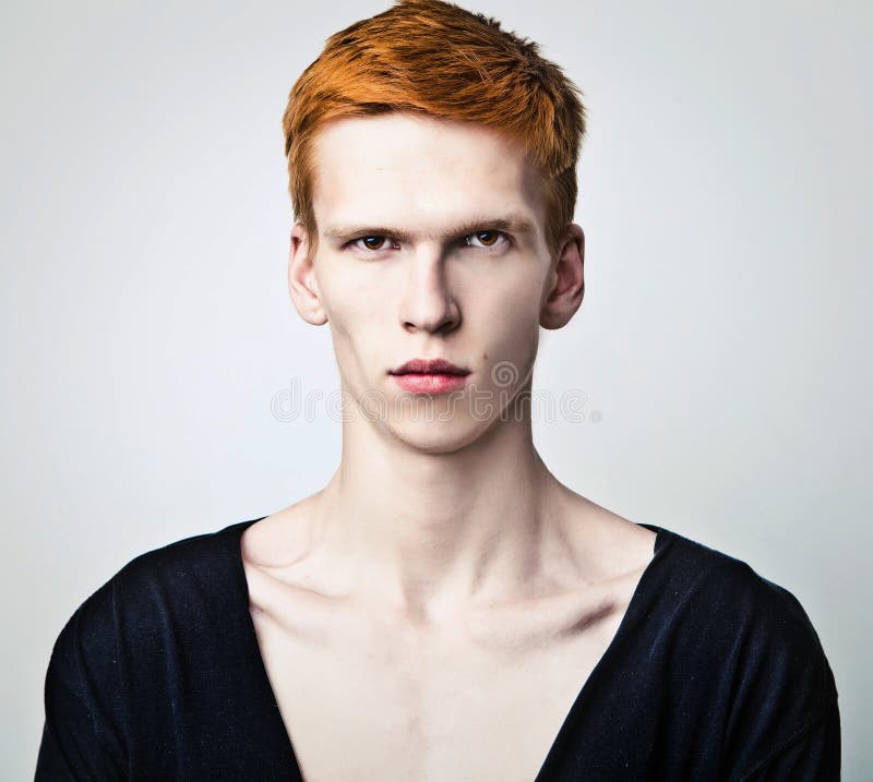 Young red haired man on light background.