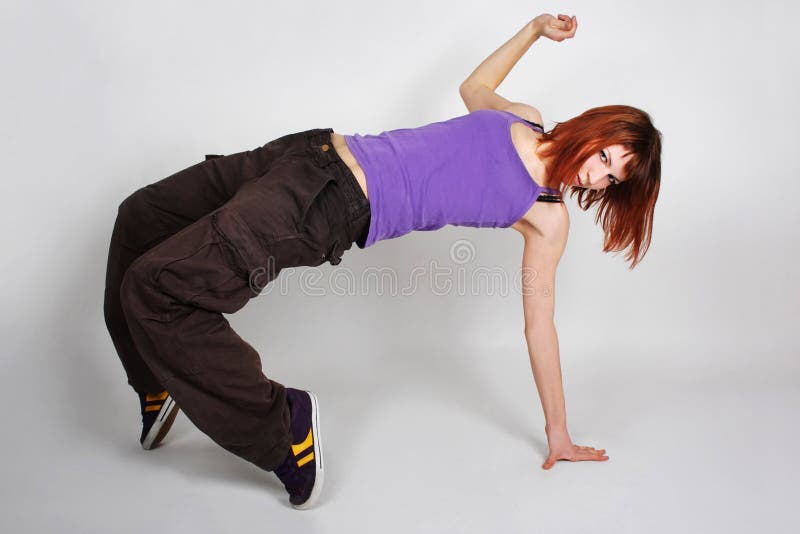 Young redhead girl in hip-hop clothes dancing